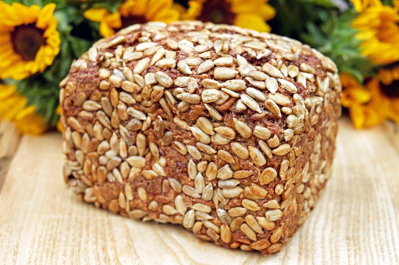 Whole grain bread and cereals on a wooden board, sources of B-group vitamins