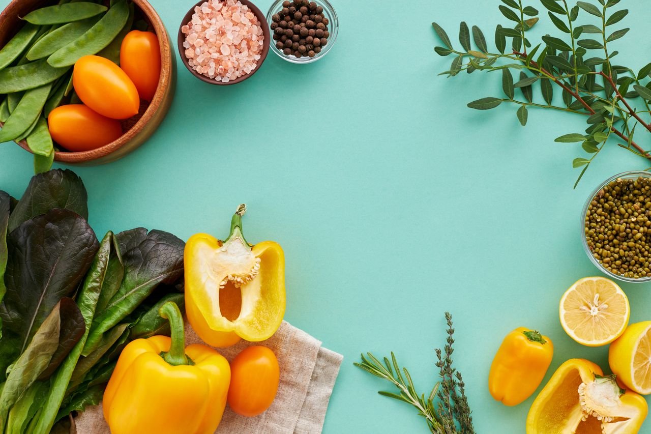 Colourful bell peppers and fresh vegetables on a teal background, foods especially rich in vitamin C